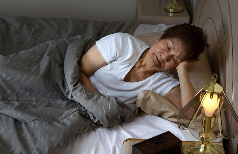 Senior woman lying in bed awake